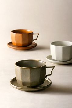 three different cups and saucers sitting next to each other