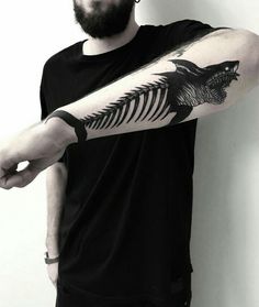 a man with a tattoo on his arm is holding onto a fish skeleton and pointing it at the viewer