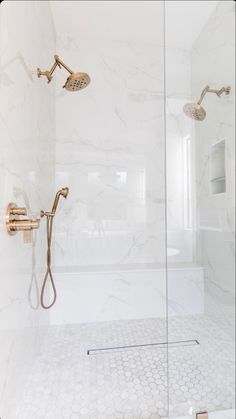 a bathroom with a glass shower door and marble tile flooring, along with white walls