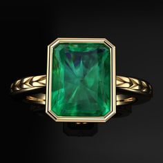 an emerald colored ring on a black background