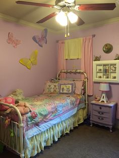 a child's bedroom decorated in pink and yellow with butterflies on the wall above the bed