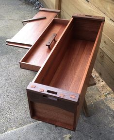 two wooden boxes sitting on the ground next to each other and one has a knife in it