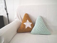 two crocheted pillows sitting on top of a white couch next to each other