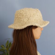 a woman with long brown hair wearing a cream colored knitted clochet hat