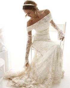 a woman in a wedding dress sitting on a chair with her hand on her knee