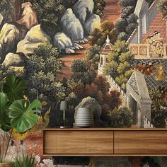 a wall with a painting on it next to a dresser and potted plant in the foreground