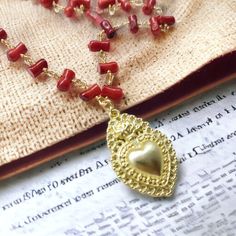 Red coral rosary necklace with sacred heart pendant. The necklace is a rosary-style necklace made of brass, with handcrafted assembly using the goldsmith's knot technique, of red coral sprigs of various sizes. The closure is with a snap hook in yellow gold plated steel. The pendant is a sacred brass heart. It represents the "votive heart" also called "ex voto" Christian religious symbol. Ex-votos have always been and still are widespread and represent one of the most timeless forms of Sicilian p Traditional Handmade Necklaces For Valentine's Day, Traditional Heart Necklace For Valentine's Day, Traditional Heart-shaped Necklace For Valentine's Day, Red Bohemian Jewelry With Heart Charm, Handmade Red Rosary For Jewelry Making, Handmade Bohemian Beaded Necklaces For Valentine's Day, Bohemian Handmade Beaded Necklaces For Valentine's Day, Spiritual Heart-shaped Brass Necklaces, Traditional Pendant Necklace For Valentine's Day