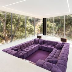 a purple couch sitting on top of a table in front of large windows with the words design the future enhance the world