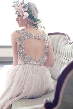 the back of a woman's dress with flowers in her hair sitting on a couch