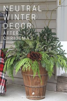 a wooden bucket filled with green plants and pine cones on the front porch next to a red plaid blanket