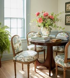 a dining room table with chairs and flowers on it