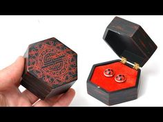 a hand holding a small wooden box with two rings in it and the lid open