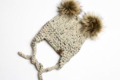 a knitted hat with two brown pom - poms on the top and bottom