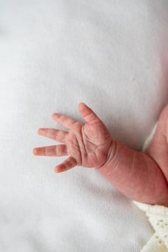 a baby's hand on top of a white blanket