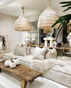 a living room filled with lots of white furniture and hanging baskets above the couches