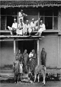 an old black and white photo of people sitting on the roof of a house with a donkey