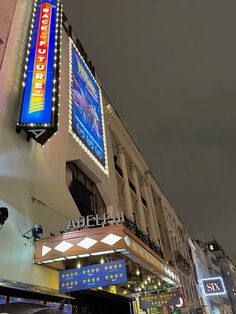 the outside of a building that is lit up at night with lights and signs on it