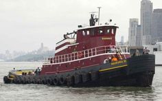 a tug boat in the water near a city