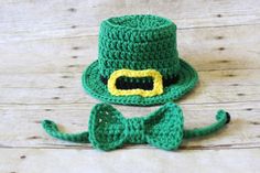 a crocheted green hat and bow tie on a wooden surface with the word,'st patrick's day'written across it