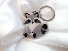 a raccoon keychain sitting on top of a white cloth