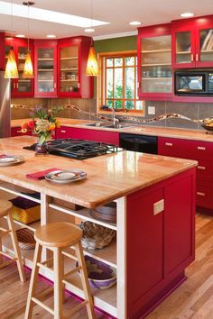 a kitchen with red cabinets and an island in front of the stove top oven is surrounded by wooden flooring