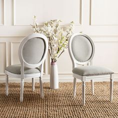 two chairs sitting next to each other on top of a carpeted floor in front of a vase with flowers