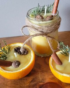 two oranges with cinnamon sticks and spices in them sitting on a table next to a mason jar