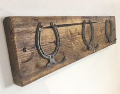 two horseshoes are mounted to the wall on a wooden board with metal hooks hanging from it