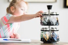 a toddler playing with a stack of jars on a table in front of a notebook