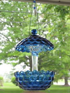 a blue glass bird feeder hanging from a window