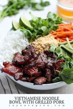 vietnamese noodle bowl with grilled pork, carrots, and greens on a white plate