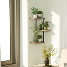 three wooden shelves with plants and vases on them in the corner of a room