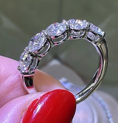 a woman's hand holding a diamond ring with three stones on the top and bottom