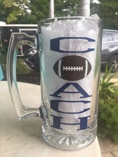 a frosty glass mug with a football on the side and letters that spell out