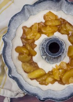 a cake pan filled with some kind of fruit on top of a wooden table next to a white towel