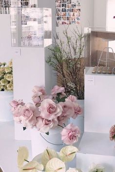 pink and white flowers in vases sitting on a table next to other flower arrangements