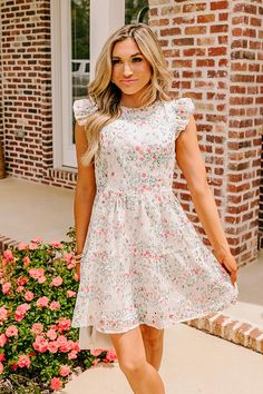 - Stroll through a field of wildflowers and twirl under the sun in this enchanting mini dress! Its flattering silhouette and delicate eyelet embroidery captures the essence of a summer daydream! - Fully lined sheer embroidered floral eyelet material with a pink and blue hued floral print -A round neckline with back button closure and a keyhole detail - Short flutter sleeves - Back zip closure - A flattering silhouette that ends in a straight mini dress length hemline Cottagecore Mini Dress For Garden Party, Cottagecore Mini Dress With Ruffles For Spring, Cute Spring Lace Mini Dress, Cute Lace Mini Dress For Spring, Spring Mini Dress With Lace Trim For Garden Party, Spring Garden Party Mini Dress With Lace Trim, Feminine Lace Floral Dress For Garden Party, White Summer Cottagecore Floral Dress, White Cottagecore Floral Dress For Summer