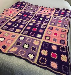 a crocheted blanket on top of a bed with white sheets and purple bedspread