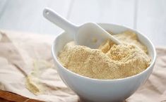 a white bowl filled with sand next to a wooden spoon on top of a table