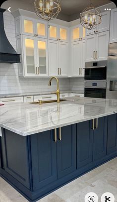 a large kitchen with marble counter tops and blue cabinets in the center is an island that has gold faucets on it