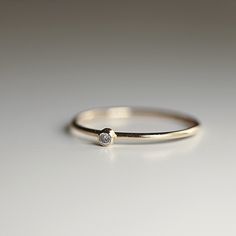 a diamond ring sitting on top of a white surface with a small diamond in the middle