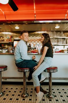 a man and woman sitting on stools in a diner