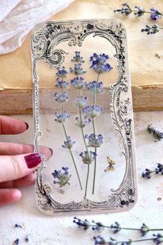 a hand holding a clear case with blue flowers in it