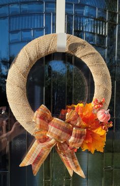 a burlap wreath with a bow and flowers on it hanging from the front door