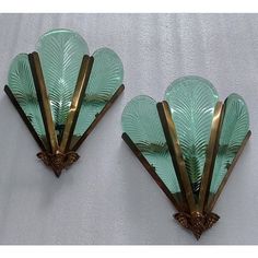 two green glass wall sconces with gold trimmings and leaves on them