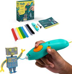 a hand holding a green toy in front of a box with markers and pens on it