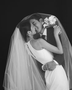 a bride and groom kissing under a veil