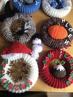 several knitted hats are arranged on a wooden table with holiday decorations around them and the words happy holidays written in large letters