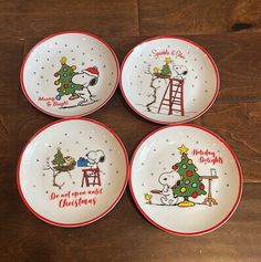 four snoopy christmas plates on a wooden table