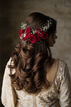 a woman with long hair wearing a red flower headpiece on her head, looking off to the side